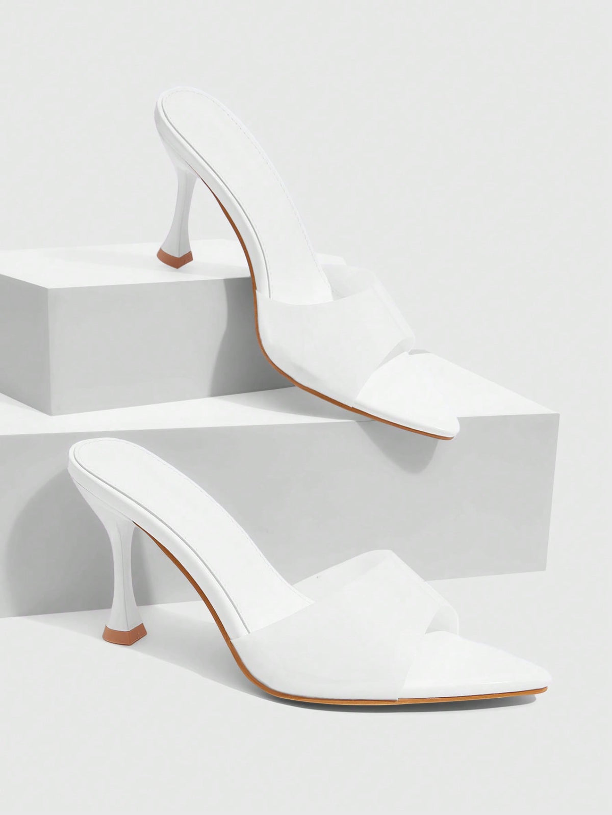 Pair of women's pointed toe stiletto mule sandals with shiny patent upper and slip-on design.
