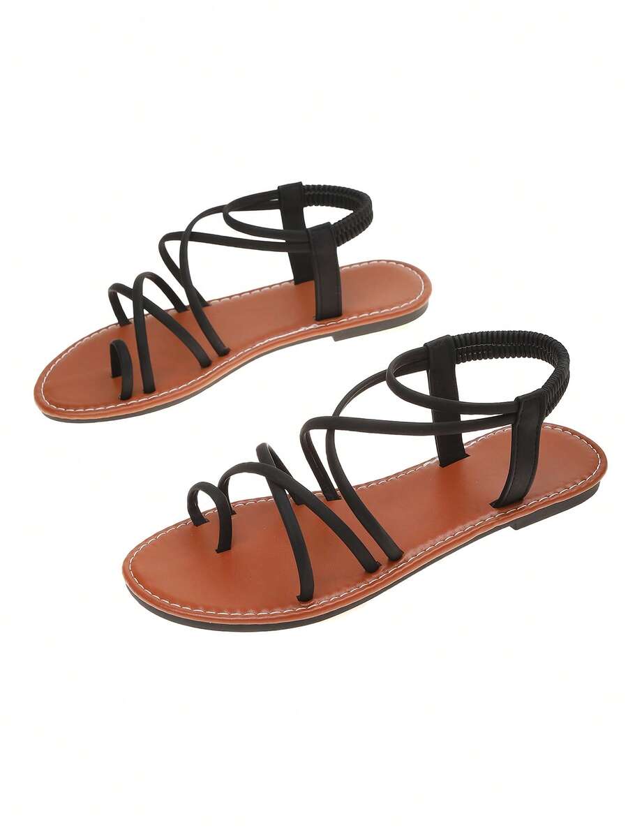 Flat sandals featuring thin criss-cross straps, elastic back strap, round toe post design, and smooth flat rubber sole.