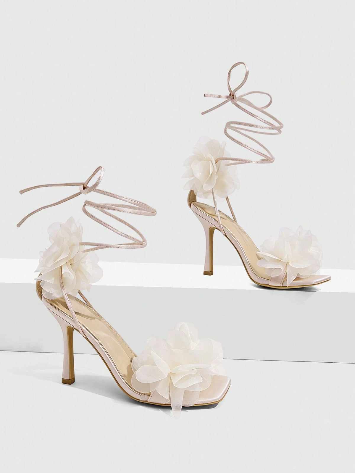 Women's open toe heeled sandals featuring 3D floral decor, satin lace-up ankle straps, and stiletto high heels.