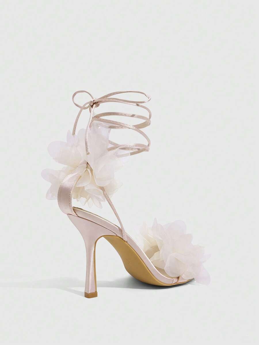 Women's open toe heeled sandals featuring 3D floral decor, satin lace-up ankle straps, and stiletto high heels.