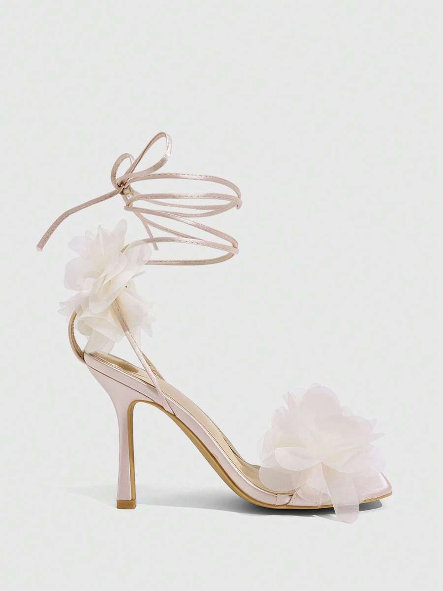 Women's open toe heeled sandals featuring 3D floral decor, satin lace-up ankle straps, and stiletto high heels.