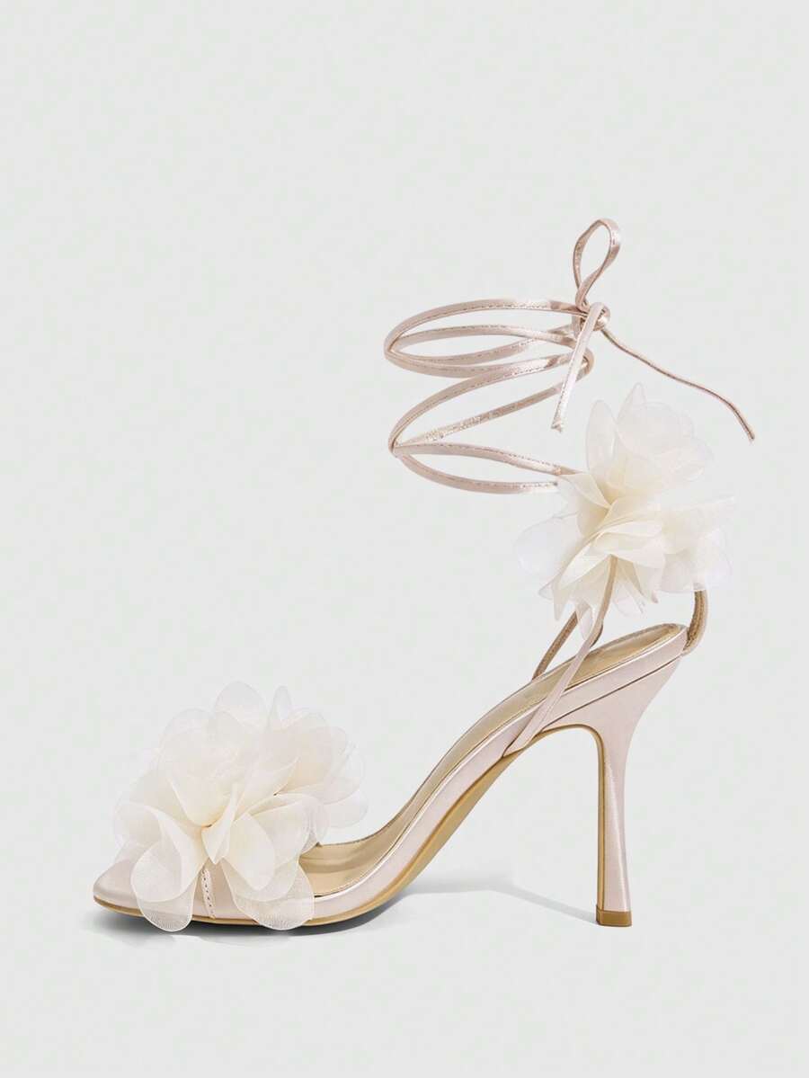 Women's open toe heeled sandals featuring 3D floral decor, satin lace-up ankle straps, and stiletto high heels.