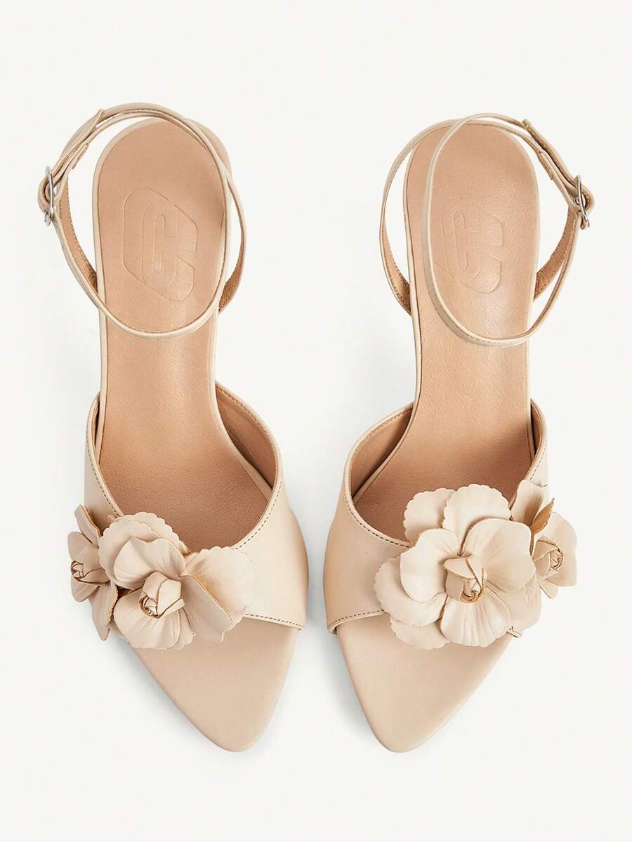 Champagne stiletto high heel sandals featuring a flower detail, open toe, and buckle back strap.