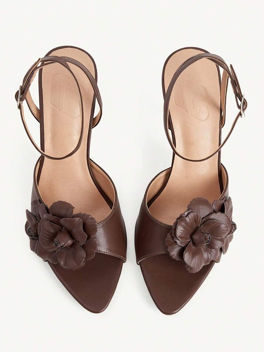 Champagne stiletto high heel sandals featuring a flower detail, open toe, and buckle back strap.