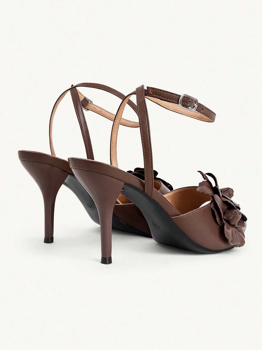 Champagne stiletto high heel sandals featuring a flower detail, open toe, and buckle back strap.