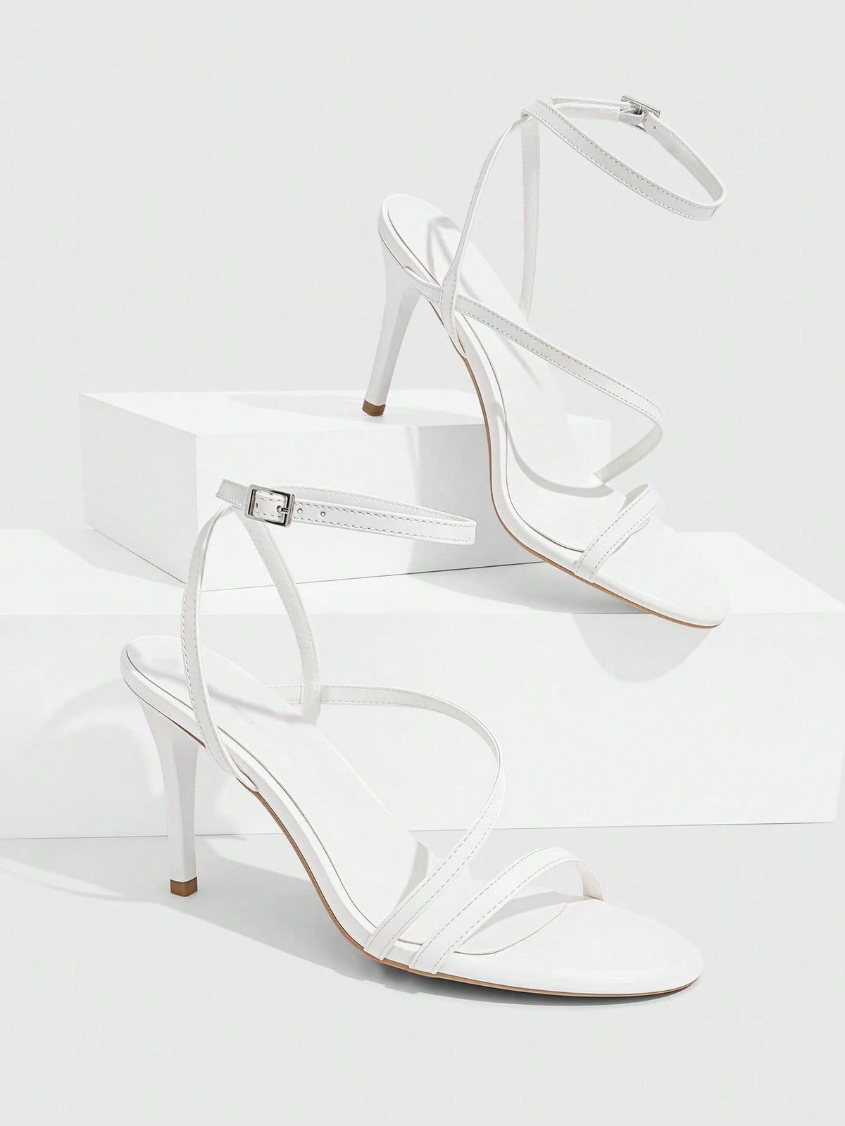 Women's silver stiletto high-heeled sandals with cross straps, buckle fastening, and open round toe.