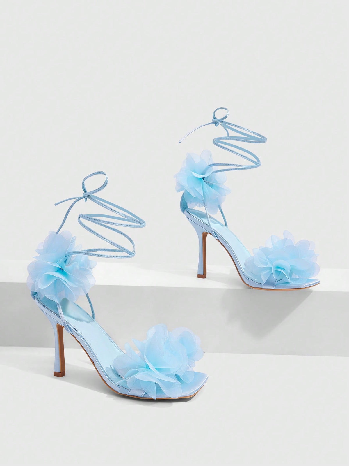 Women's open toe heeled sandals featuring 3D floral decor, satin lace-up ankle straps, and stiletto high heels.