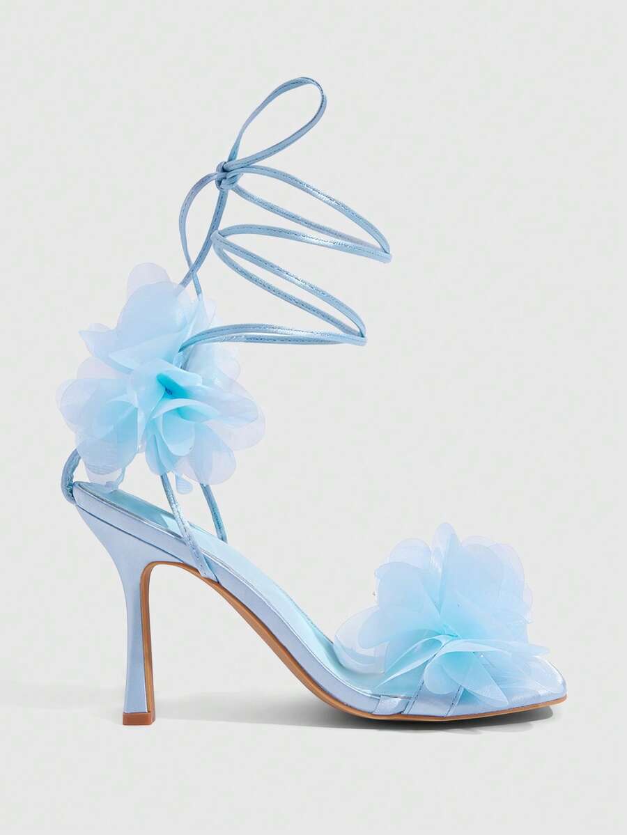 Women's open toe heeled sandals featuring 3D floral decor, satin lace-up ankle straps, and stiletto high heels.