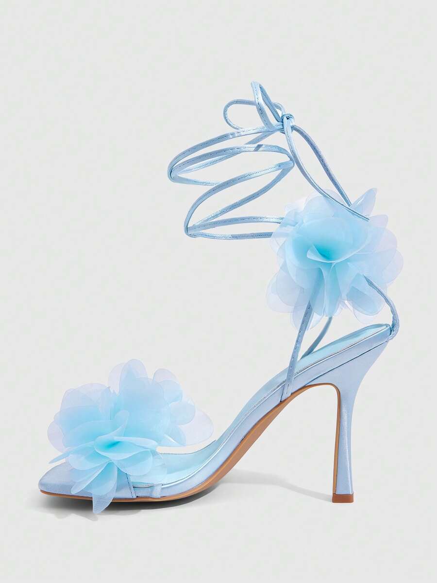 Women's open toe heeled sandals featuring 3D floral decor, satin lace-up ankle straps, and stiletto high heels.