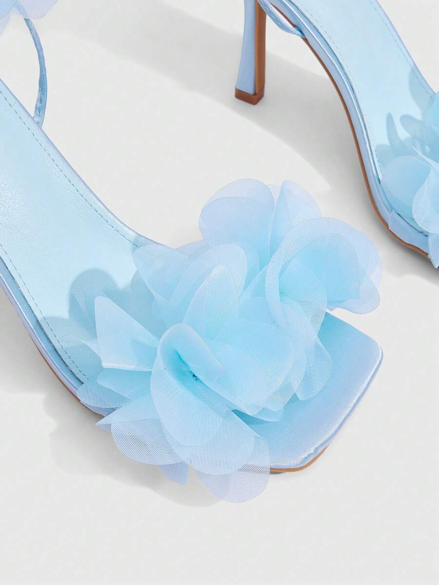 Women's open toe heeled sandals featuring 3D floral decor, satin lace-up ankle straps, and stiletto high heels.