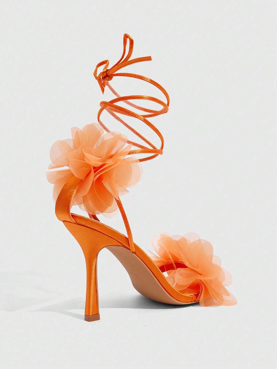 Women's open toe heeled sandals featuring 3D floral decor, satin lace-up ankle straps, and stiletto high heels.