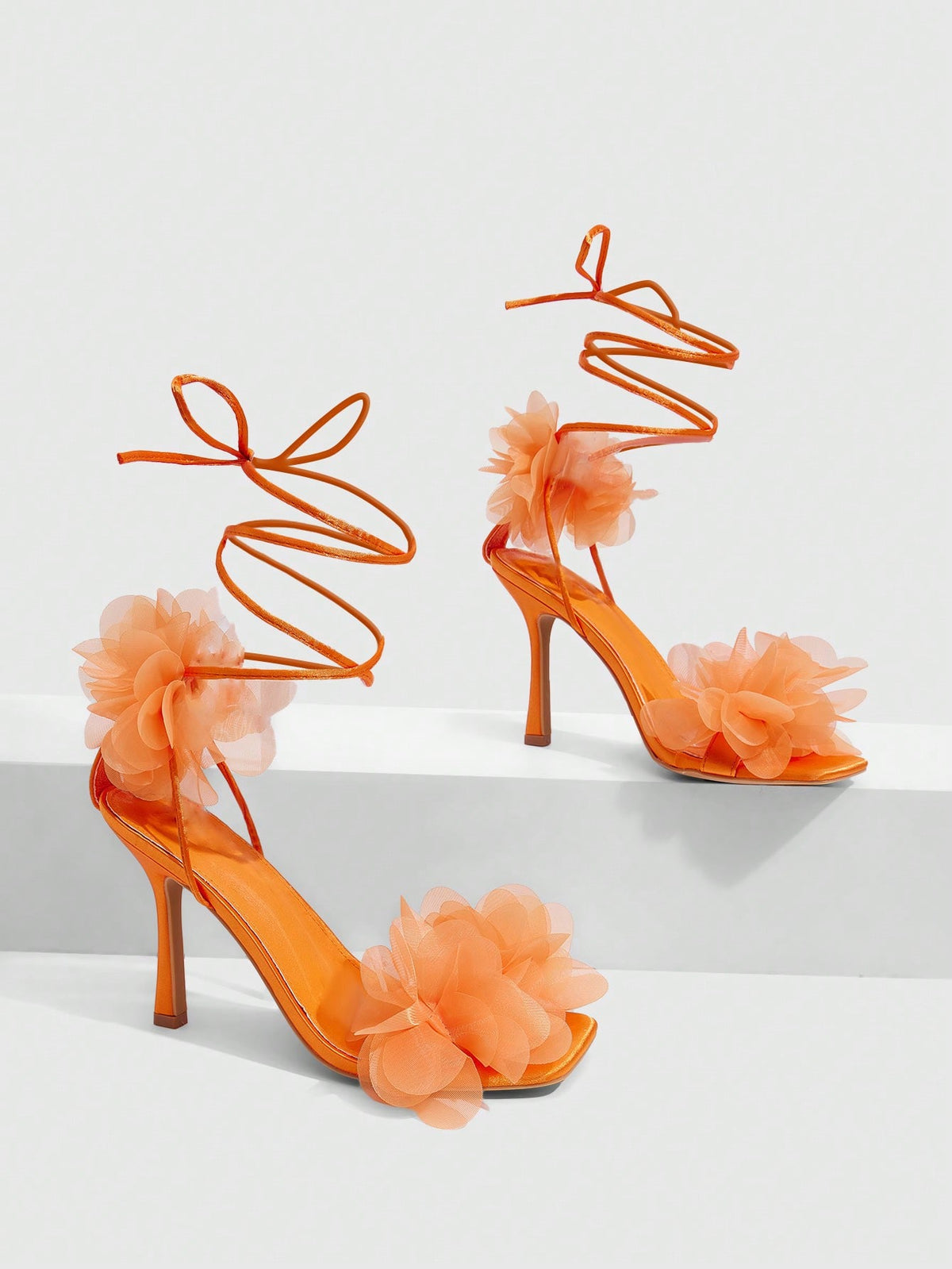 Women's open toe heeled sandals featuring 3D floral decor, satin lace-up ankle straps, and stiletto high heels.