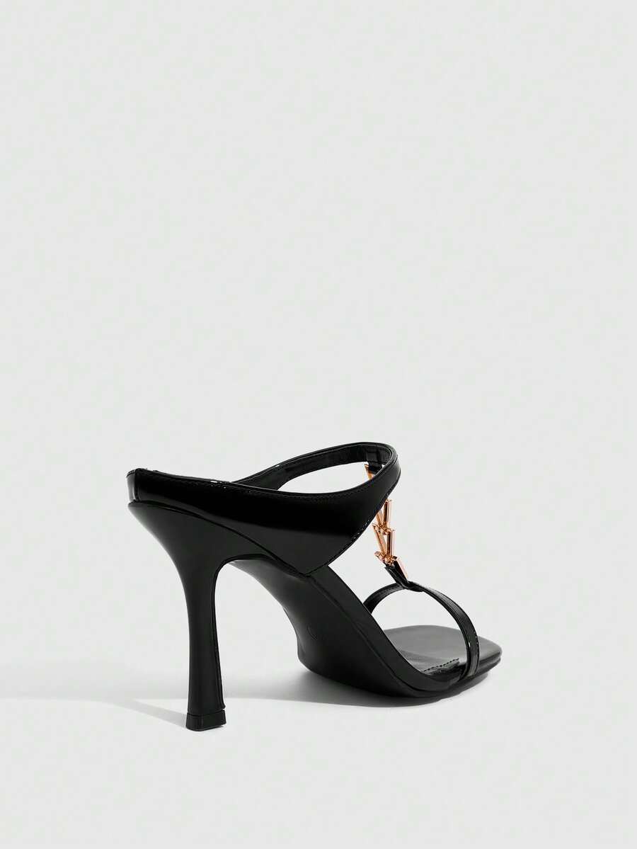 Women's black patent leather slip-on heeled sandals featuring a square toe, gold metal hardware, and sleek stiletto heels.