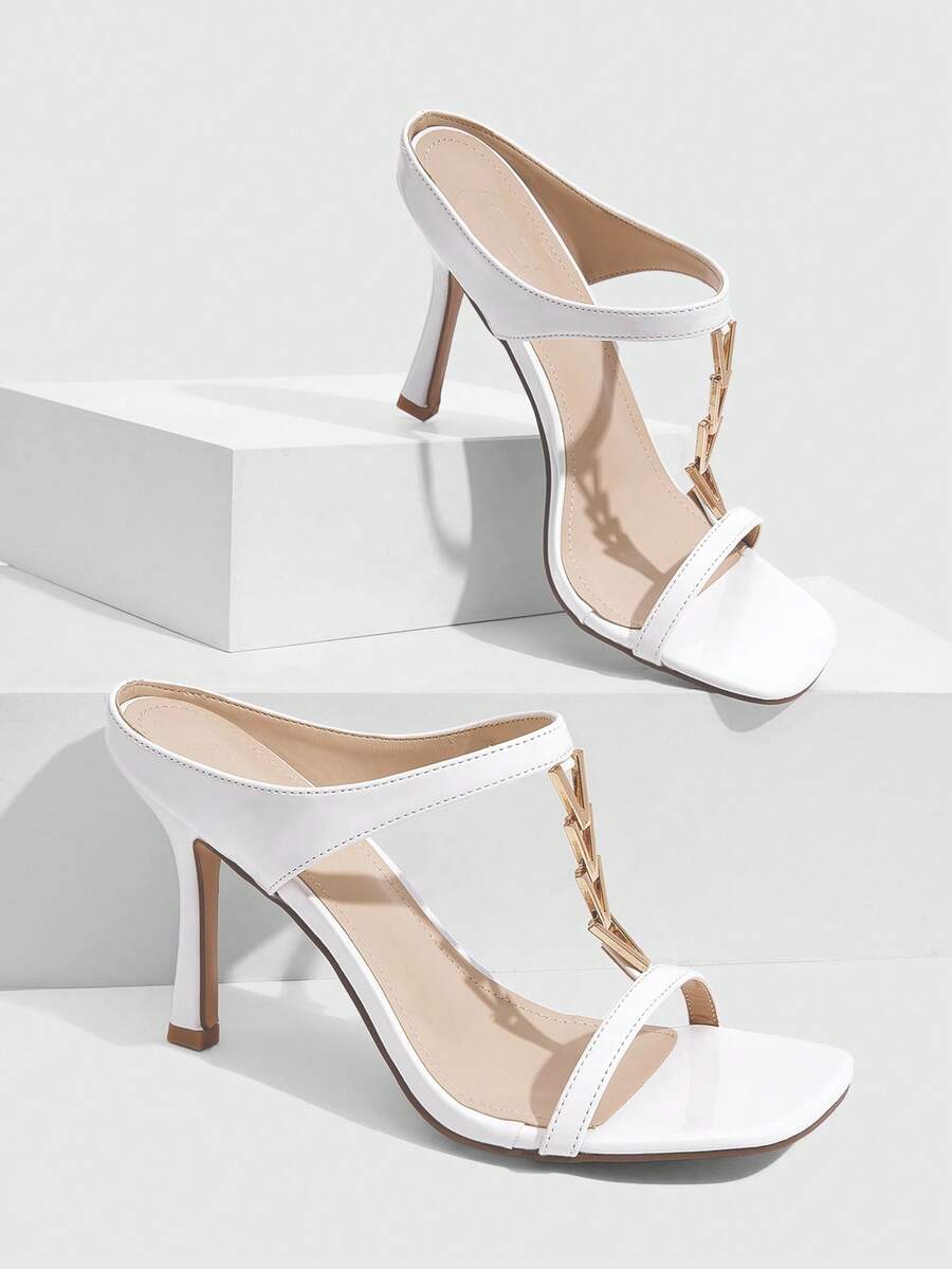 Women's black patent leather slip-on heeled sandals featuring a square toe, gold metal hardware, and sleek stiletto heels.