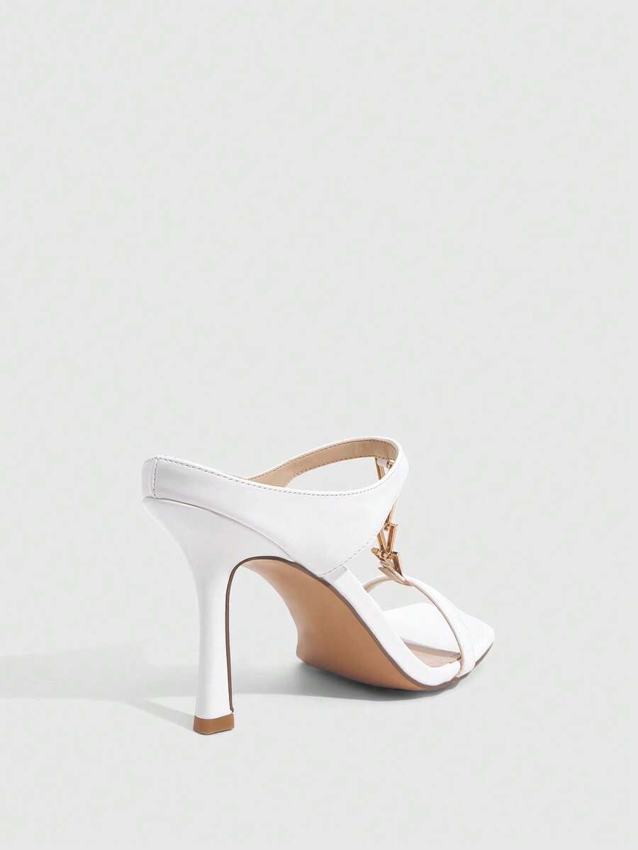 Women's black patent leather slip-on heeled sandals featuring a square toe, gold metal hardware, and sleek stiletto heels.
