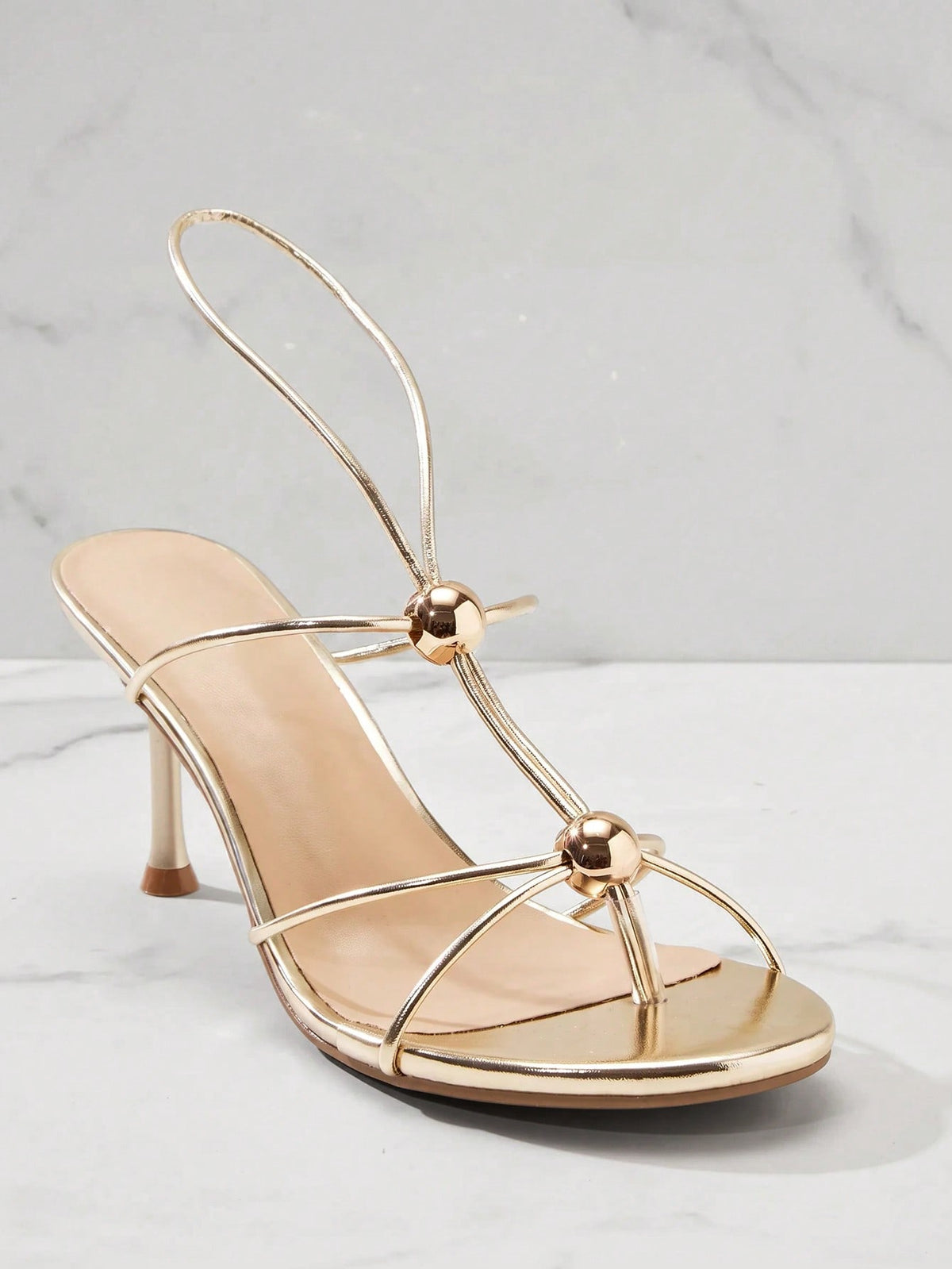 Women's strappy stiletto heel sandals crafted in vegan PU leather featuring open toe design and metallic bead accents.