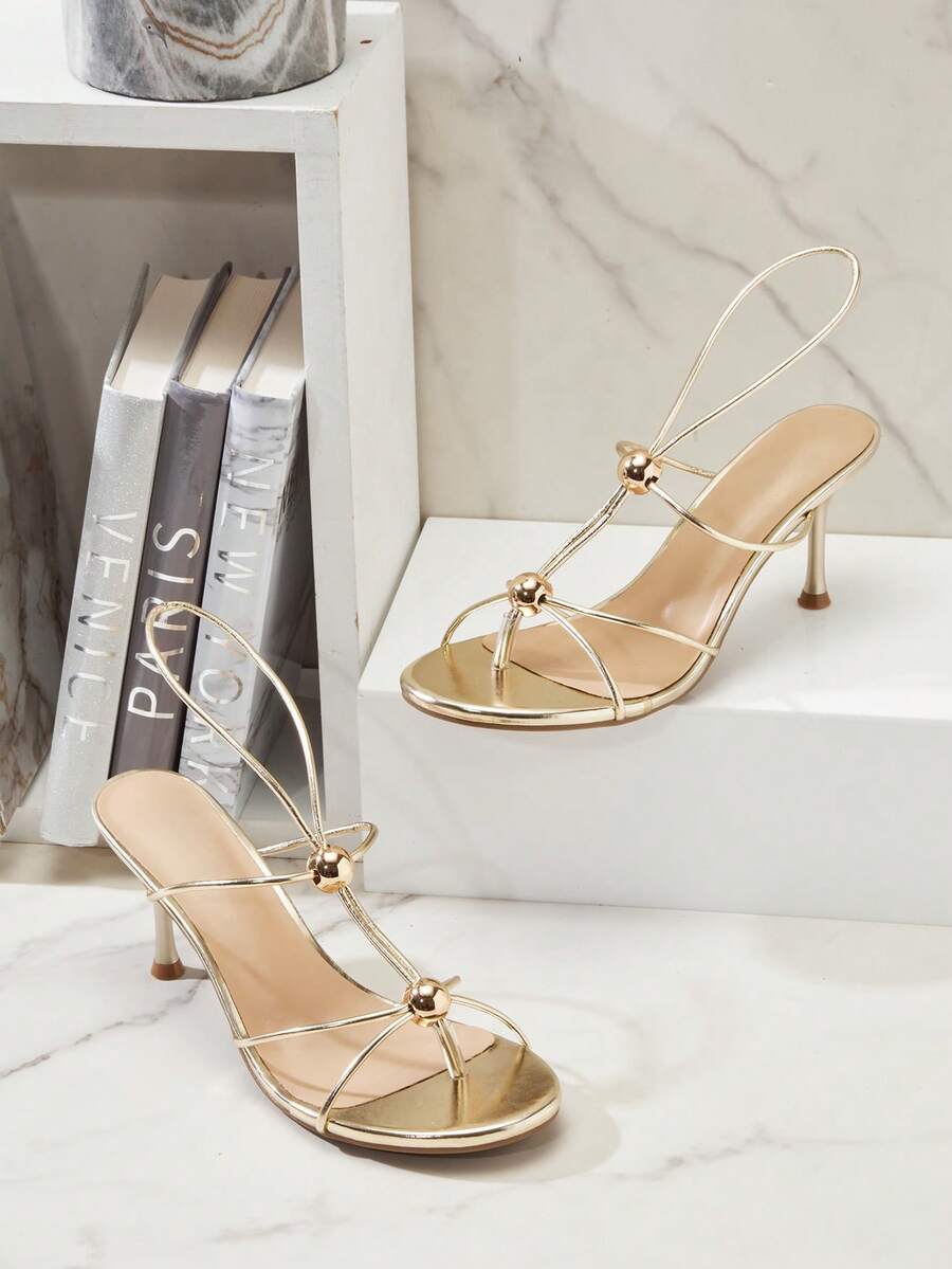 Women's strappy stiletto heel sandals crafted in vegan PU leather featuring open toe design and metallic bead accents.