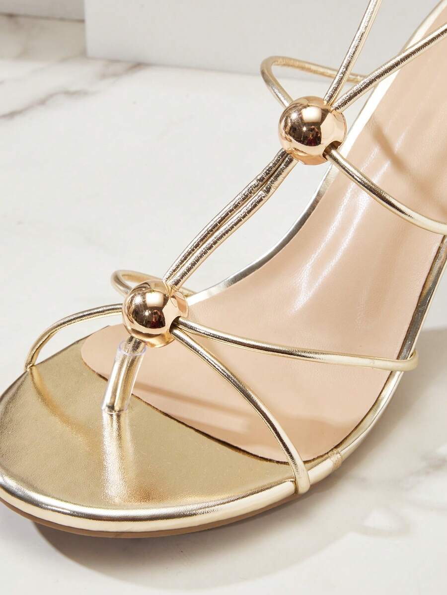 Women's strappy stiletto heel sandals crafted in vegan PU leather featuring open toe design and metallic bead accents.