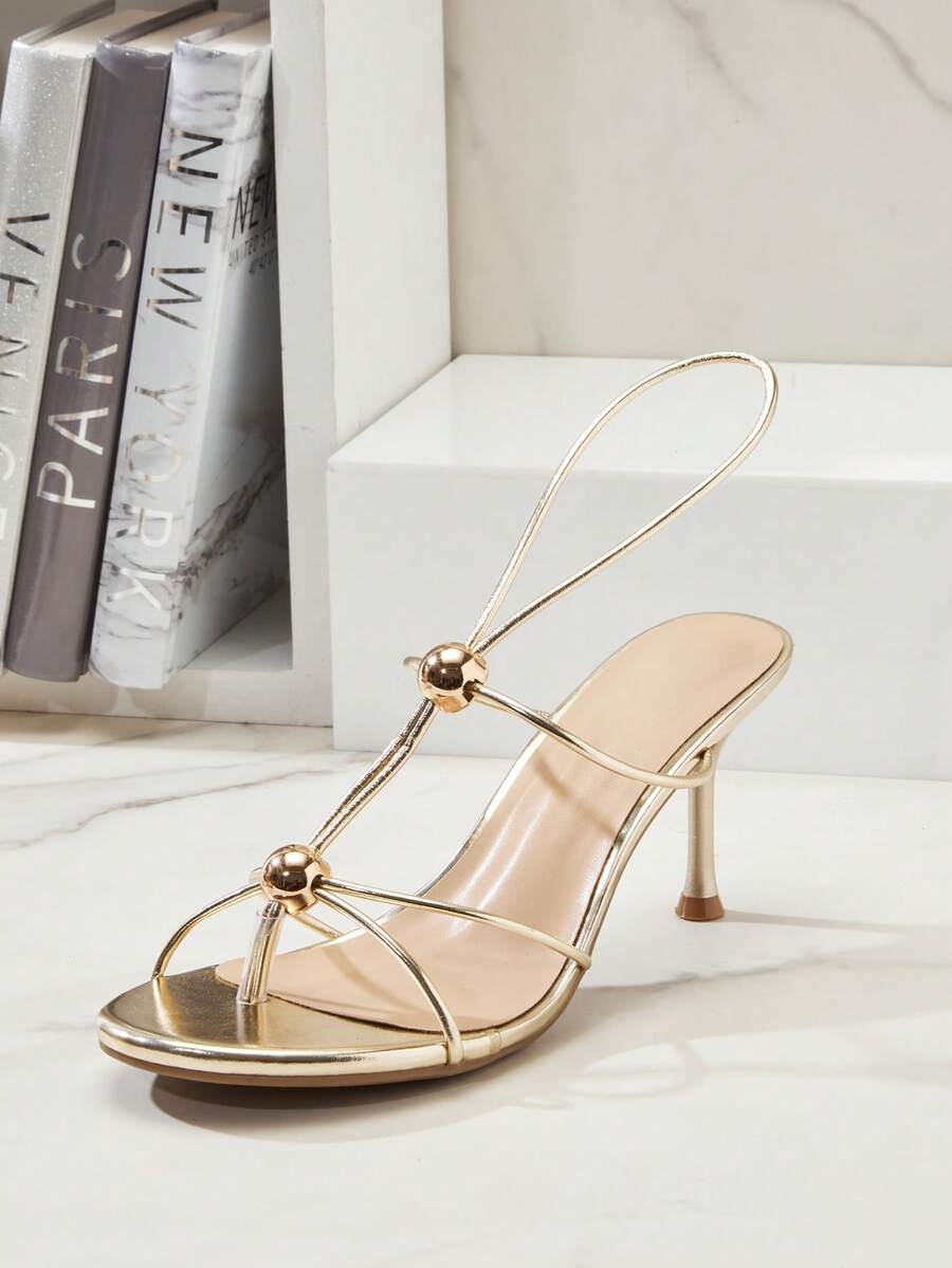 Women's strappy stiletto heel sandals crafted in vegan PU leather featuring open toe design and metallic bead accents.