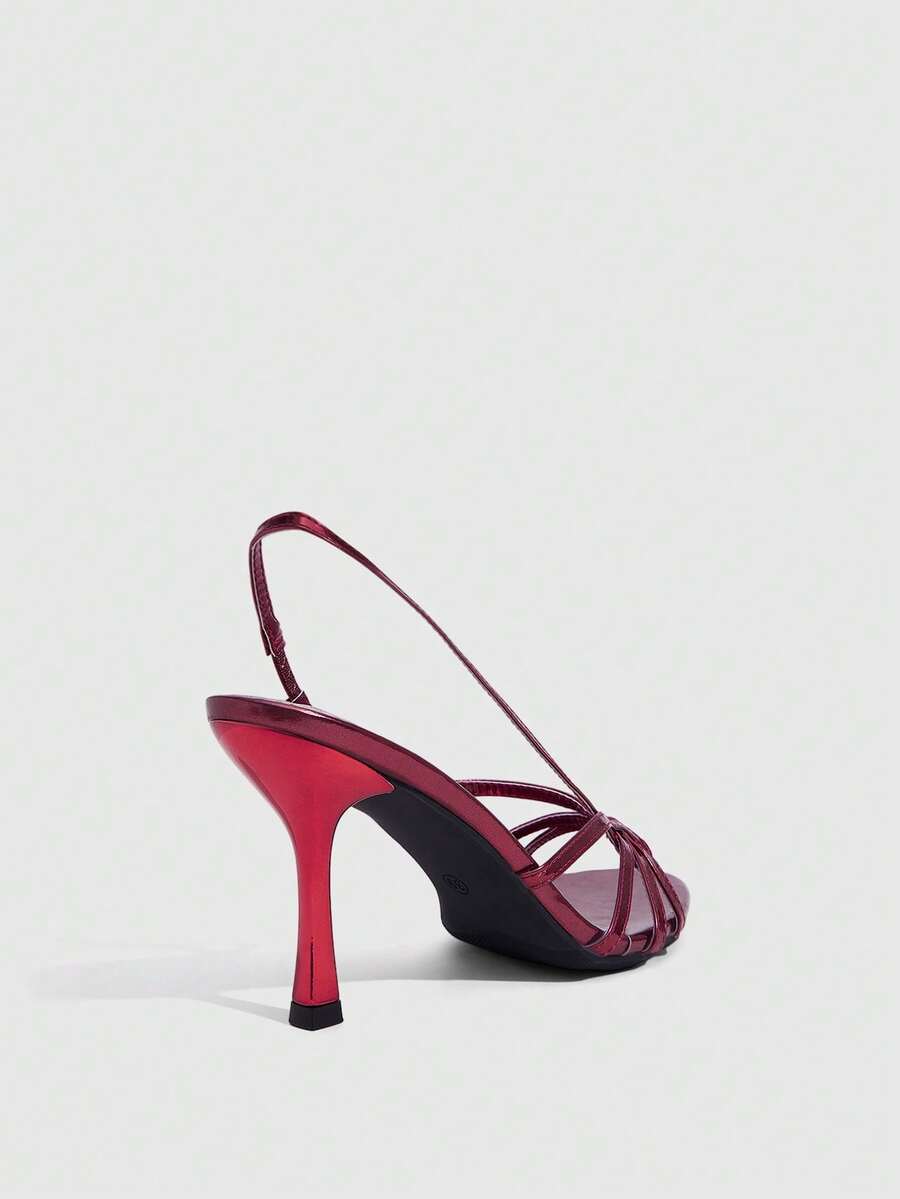 Women's open-toed stiletto high-heeled sandals in glossy patent black featuring twist strap detailing and slingback design.