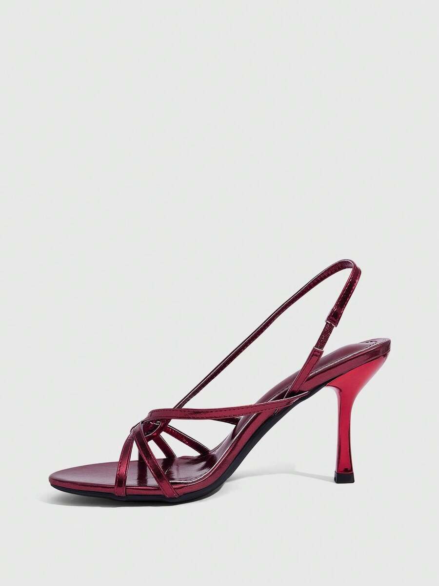 Women's open-toed stiletto high-heeled sandals in glossy patent black featuring twist strap detailing and slingback design.