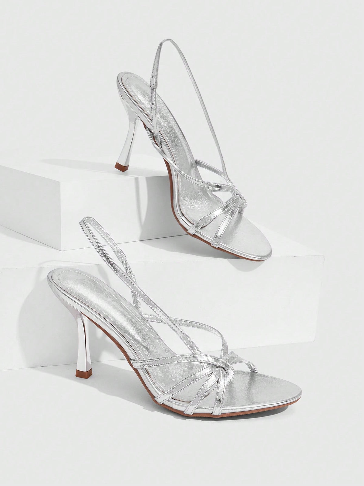 Women's open-toed stiletto high-heeled sandals in glossy patent black featuring twist strap detailing and slingback design.