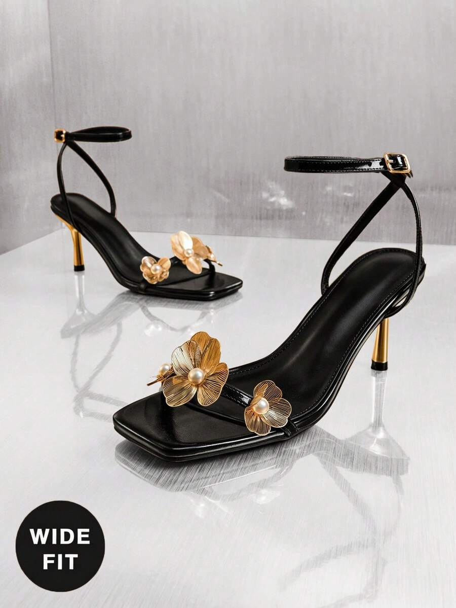 Women's metallic gold wide-fit high heeled sandals featuring stiletto heels, open toe straps, and elegant floral appliques.