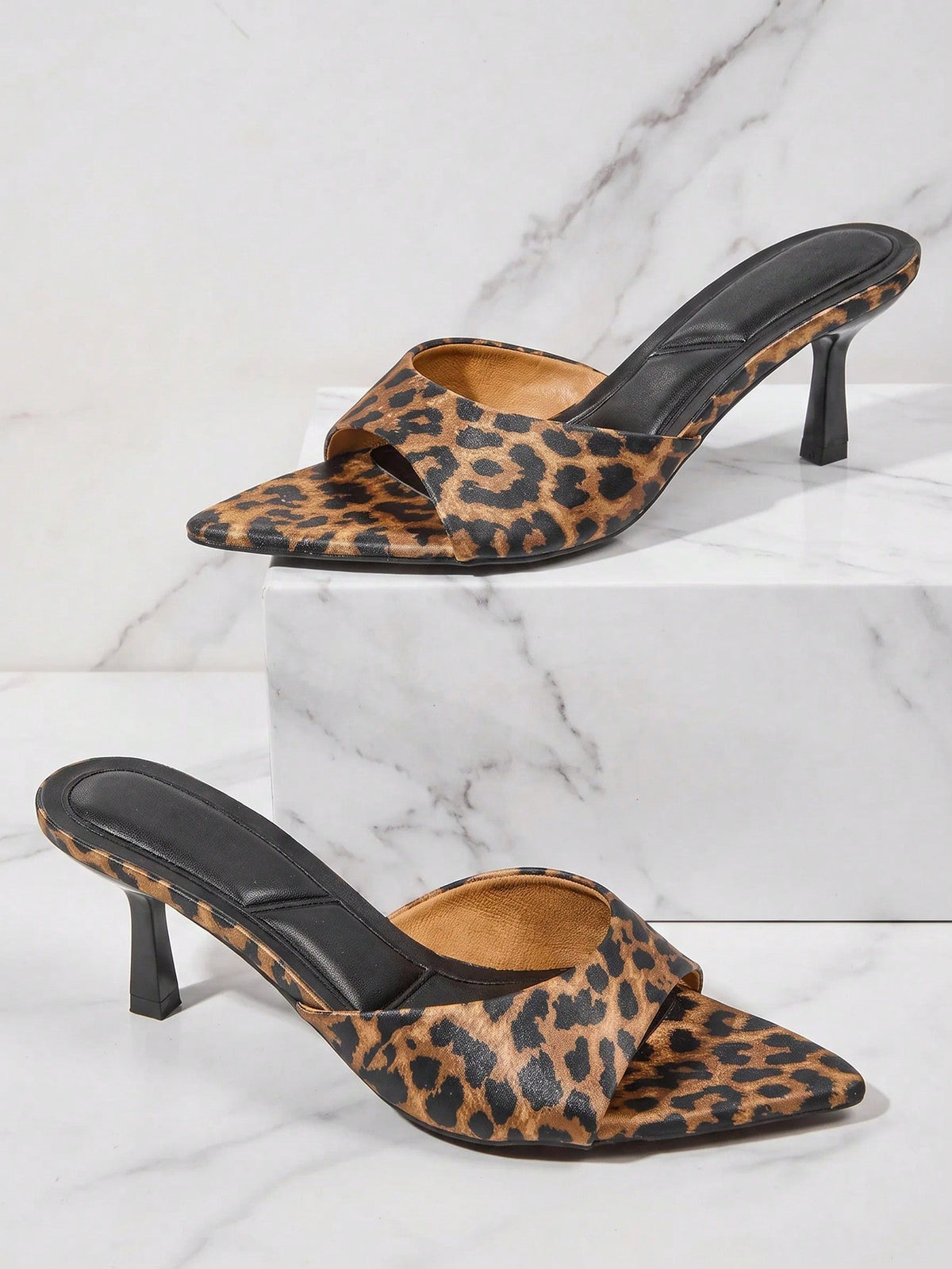 Black pointy toe kitten heel shoes for women featuring a sleek cut out mule design and glossy patent leather finish.