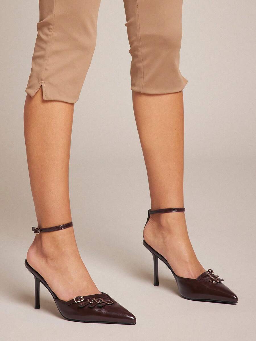 Women's pointed toe stiletto heel slingback pumps in chocolate brown with double metal buckle strap details.