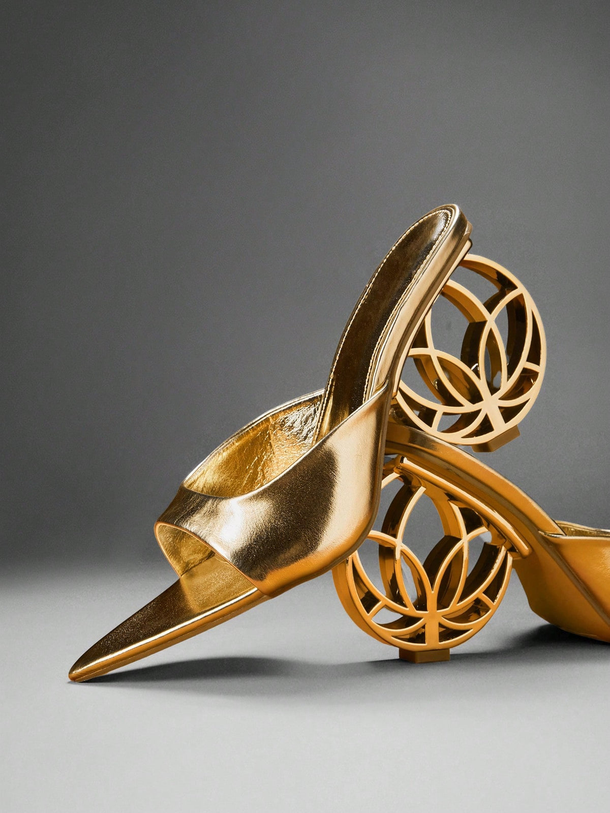 Women's slip-on heeled sandals in gold PU leather featuring a pointed toe and sculptural ball-shaped mid heel.