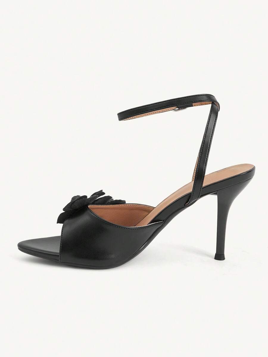 Champagne stiletto high heel sandals featuring a flower detail, open toe, and buckle back strap.