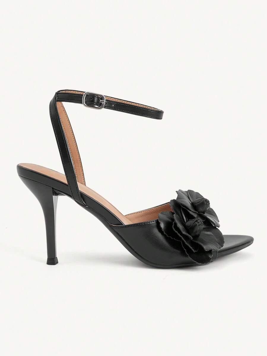 Champagne stiletto high heel sandals featuring a flower detail, open toe, and buckle back strap.
