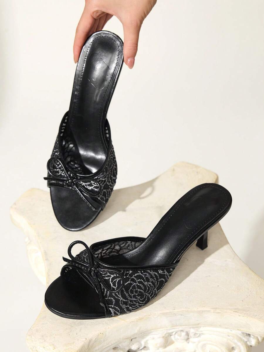 Open toe high heel slide sandals featuring lace details and a bow accent on the upper strap.