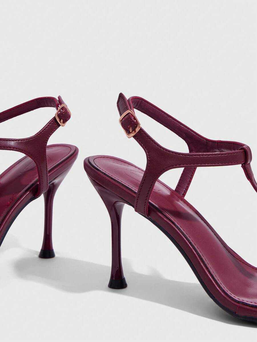 Women's open toe stiletto high heel sandals with T-strap design and adjustable ankle buckle closure in sleek PU leather.