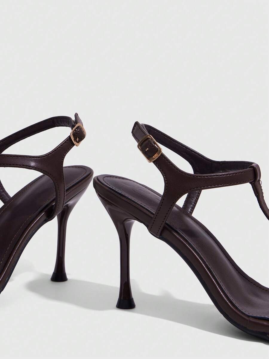 Women's open toe stiletto high heel sandals with T-strap design and adjustable ankle buckle closure in sleek PU leather.