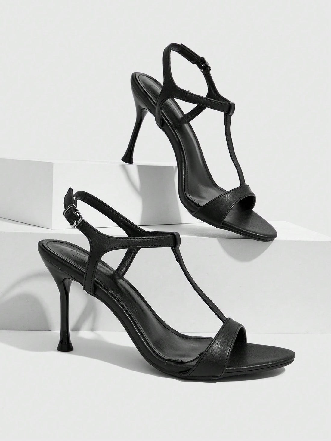 Women's open toe stiletto high heel sandals with T-strap design and adjustable ankle buckle closure in sleek PU leather.
