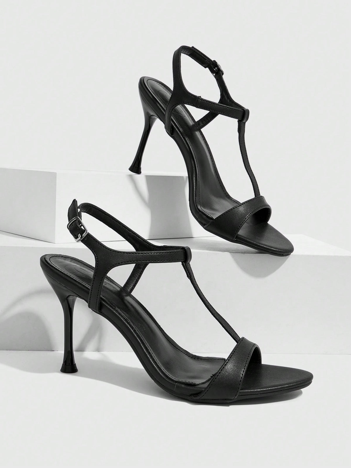 Women's open toe stiletto high heel sandals with T-strap design and adjustable ankle buckle closure in sleek PU leather.