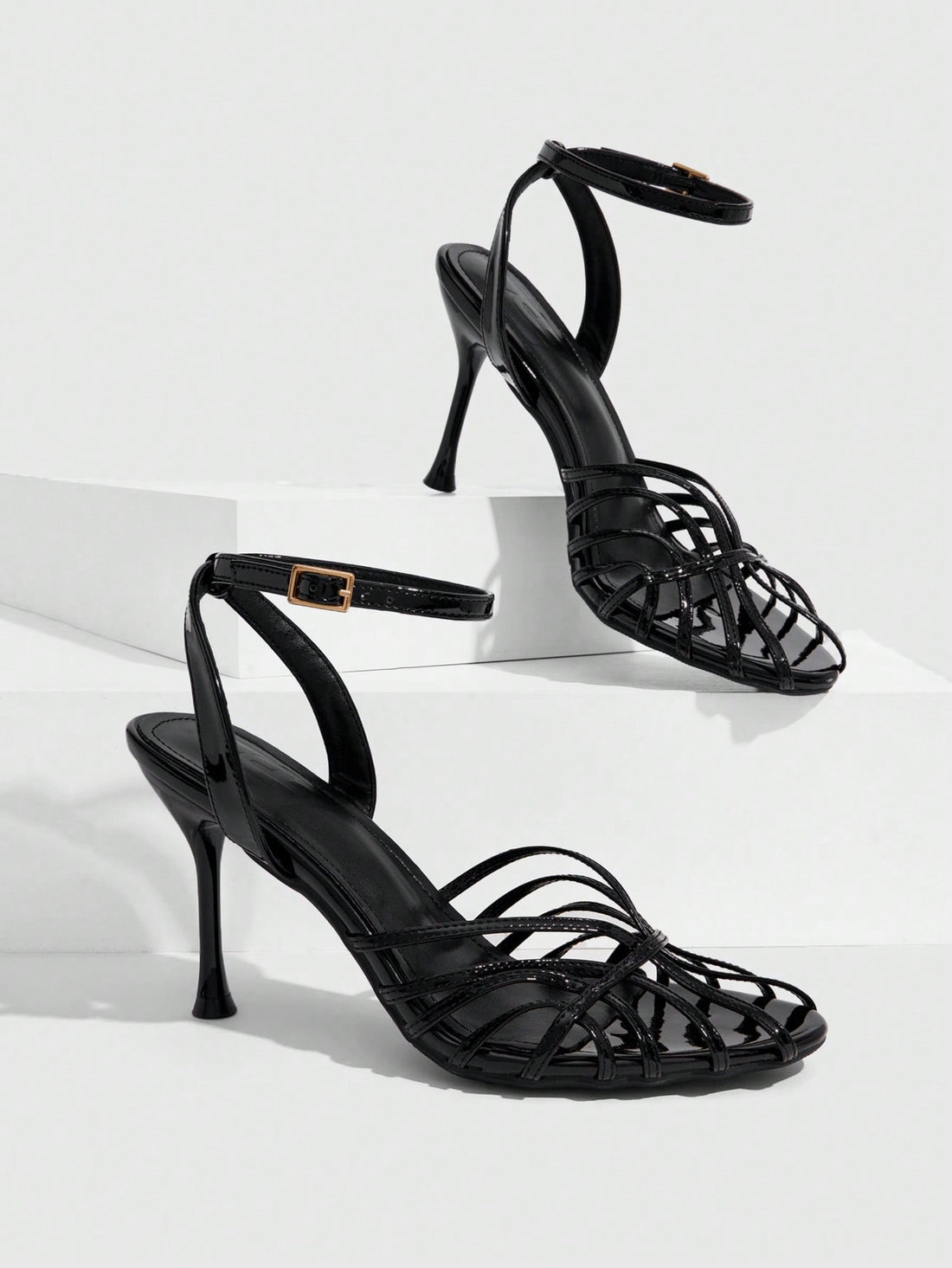 Women's glossy silver open-toed sandals with thin pyramid heel and strappy ribbon details.