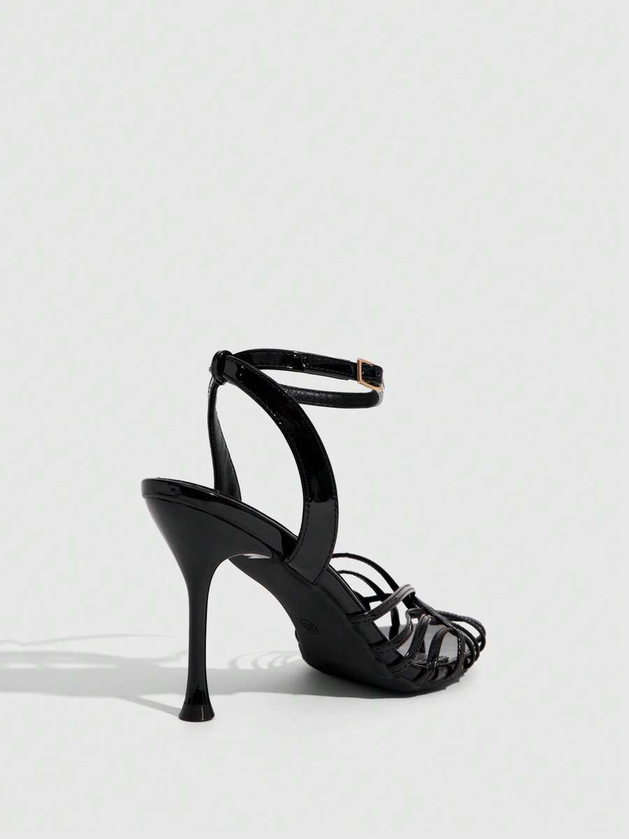 Women's glossy silver open-toed sandals with thin pyramid heel and strappy ribbon details.
