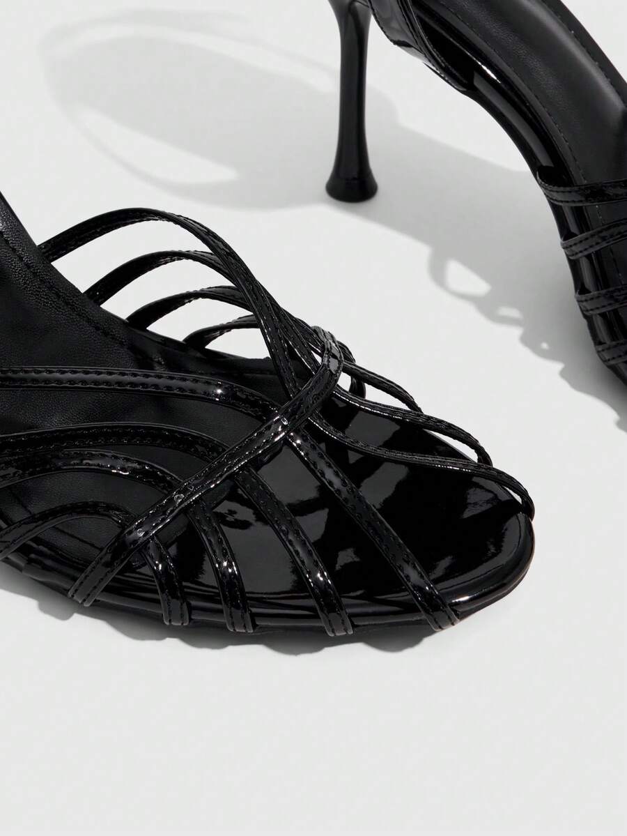 Women's glossy silver open-toed sandals with thin pyramid heel and strappy ribbon details.