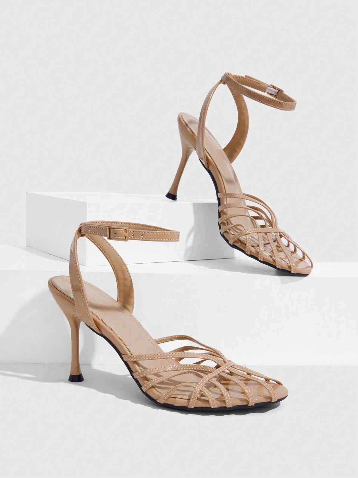 Women's glossy silver open-toed sandals with thin pyramid heel and strappy ribbon details.