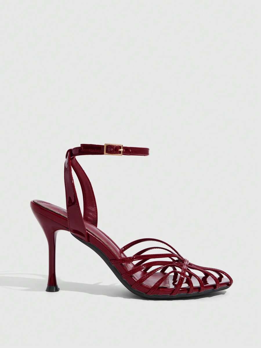 Women's glossy silver open-toed sandals with thin pyramid heel and strappy ribbon details.