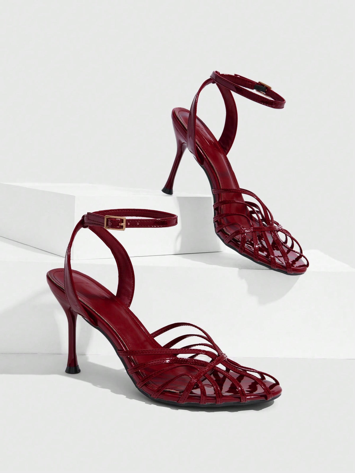 Women's glossy silver open-toed sandals with thin pyramid heel and strappy ribbon details.