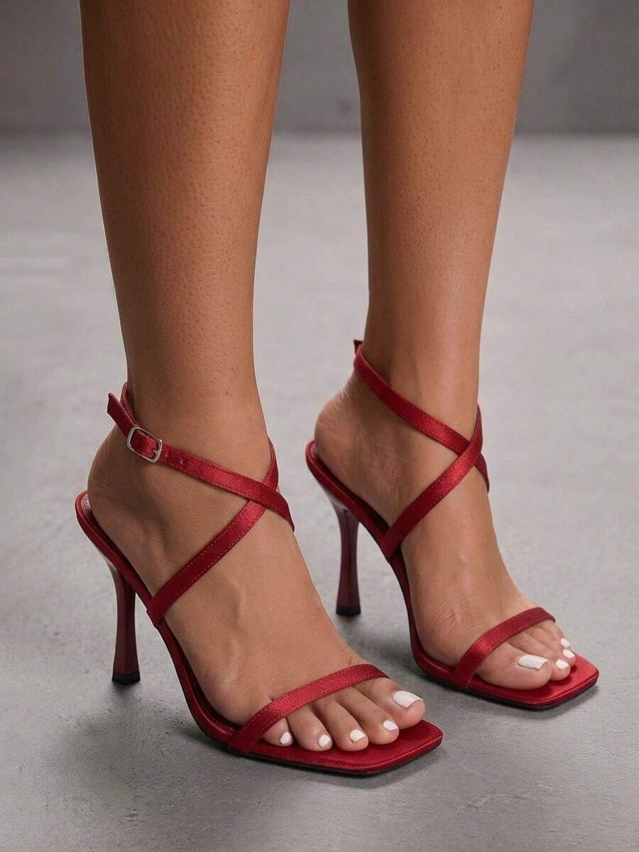 Pair of women's brown satin open toe stiletto sandals with cross ankle buckle straps.