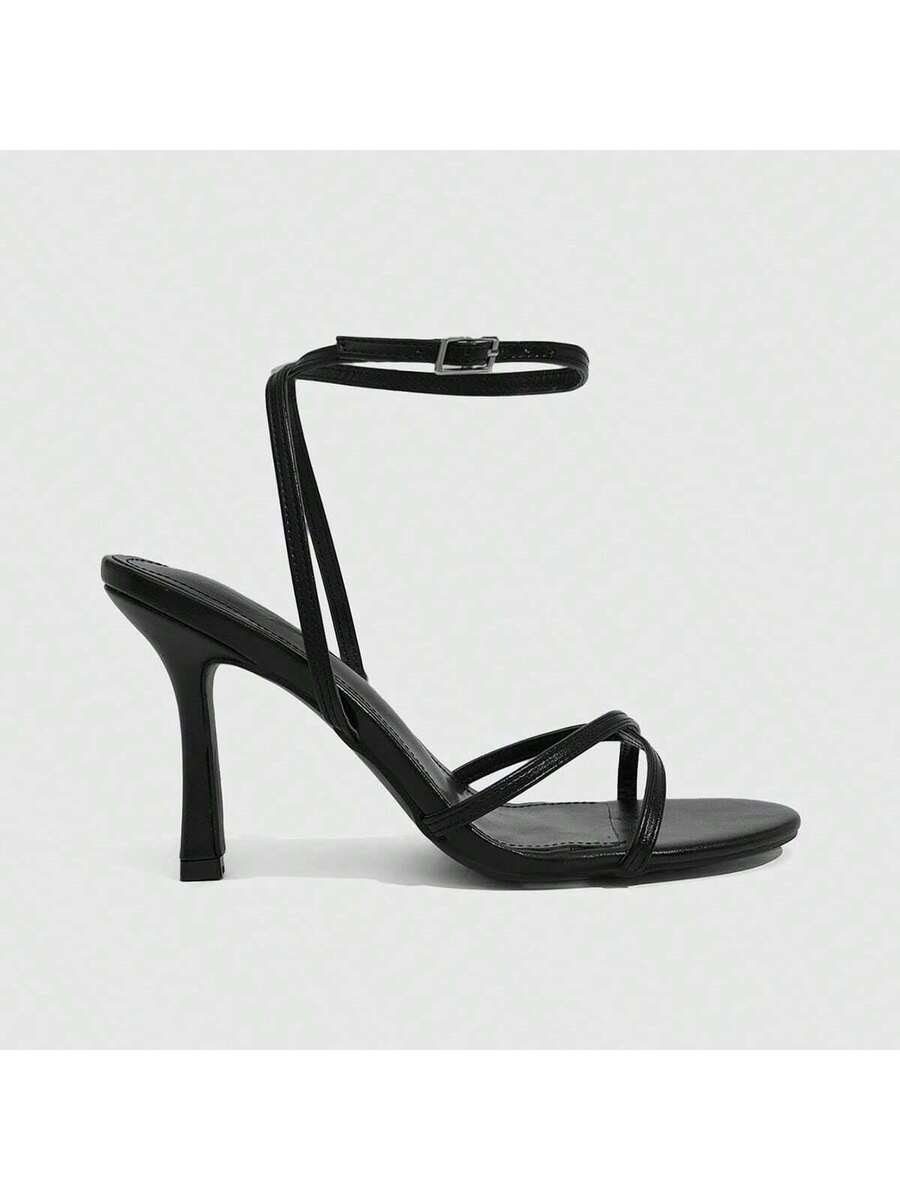 Pair of cream open-toe heeled sandals featuring crisscross front straps, a sleek stiletto high heel, and an adjustable ankle strap with buckle closure.