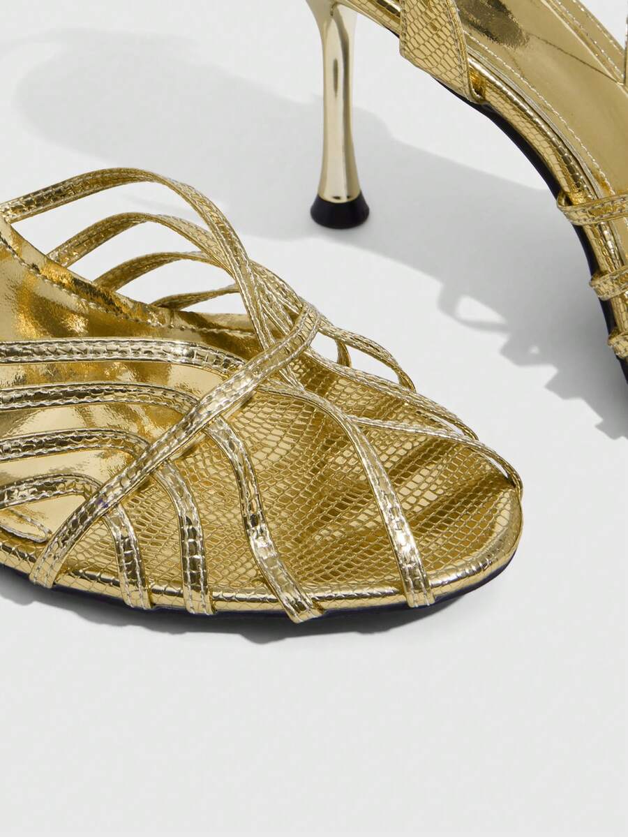 Women's glossy silver open-toed sandals with thin pyramid heel and strappy ribbon details.