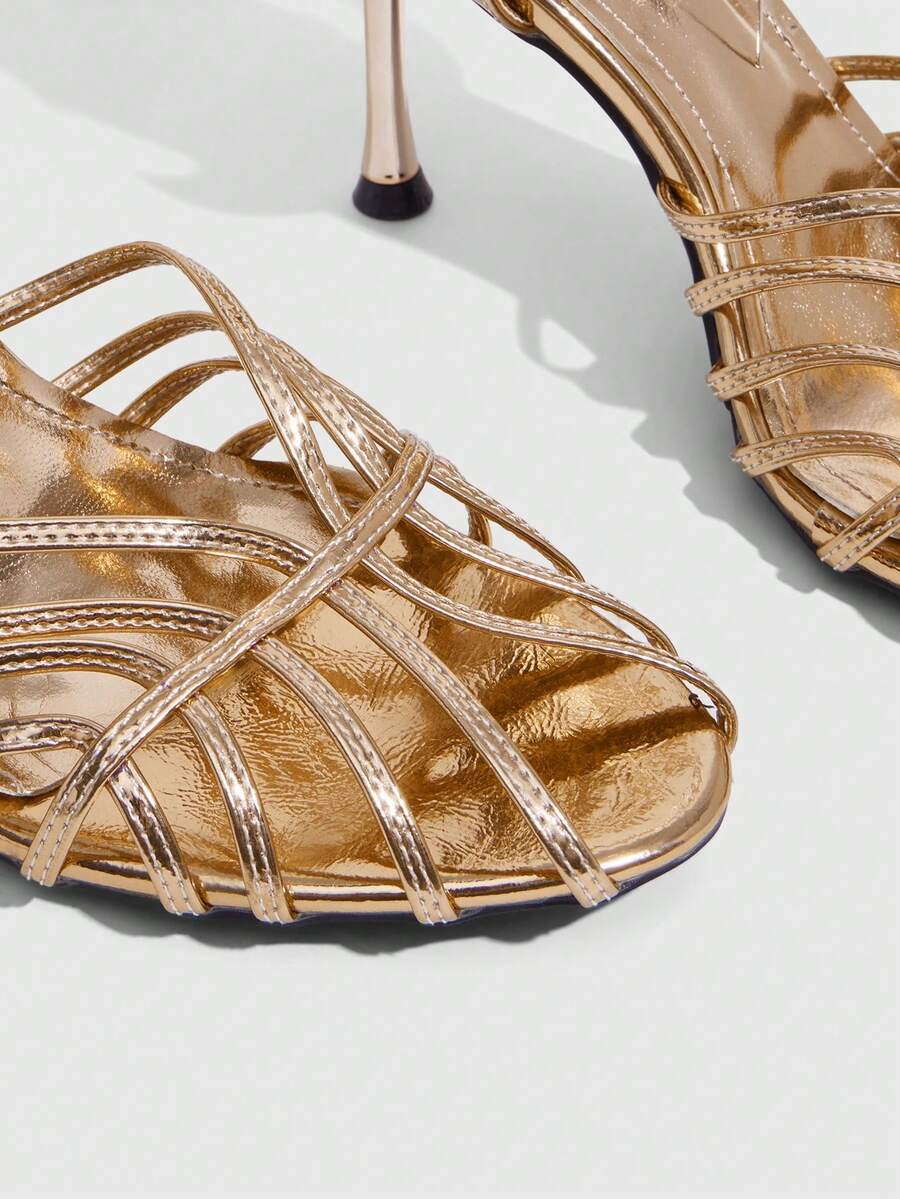 Women's glossy silver open-toed sandals with thin pyramid heel and strappy ribbon details.