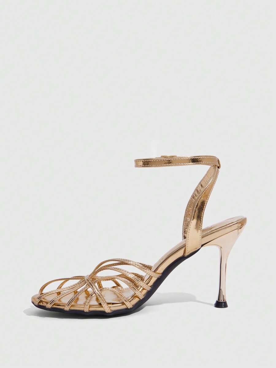 Women's glossy silver open-toed sandals with thin pyramid heel and strappy ribbon details.