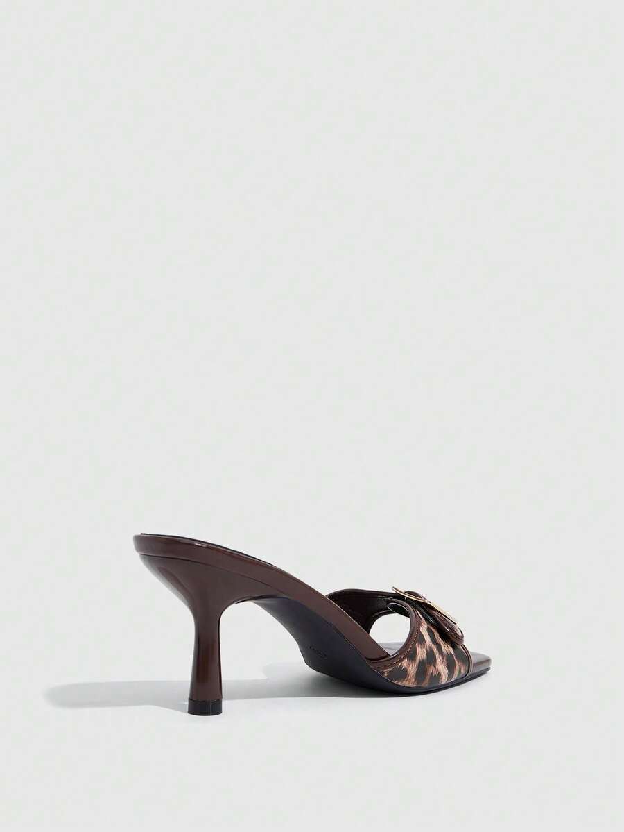 Beige women's slip-on kitten heel slide sandals featuring an accent buckle with grommet eyelets.