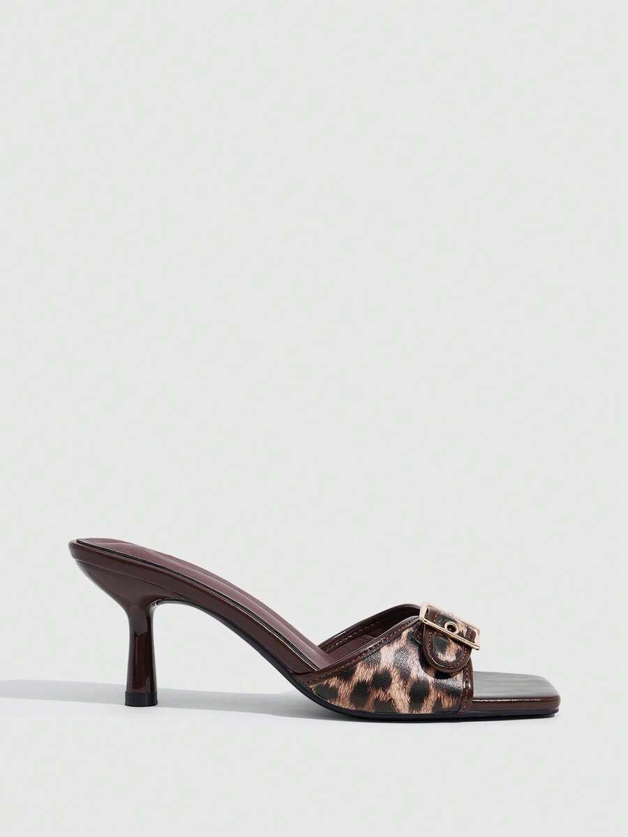 Beige women's slip-on kitten heel slide sandals featuring an accent buckle with grommet eyelets.
